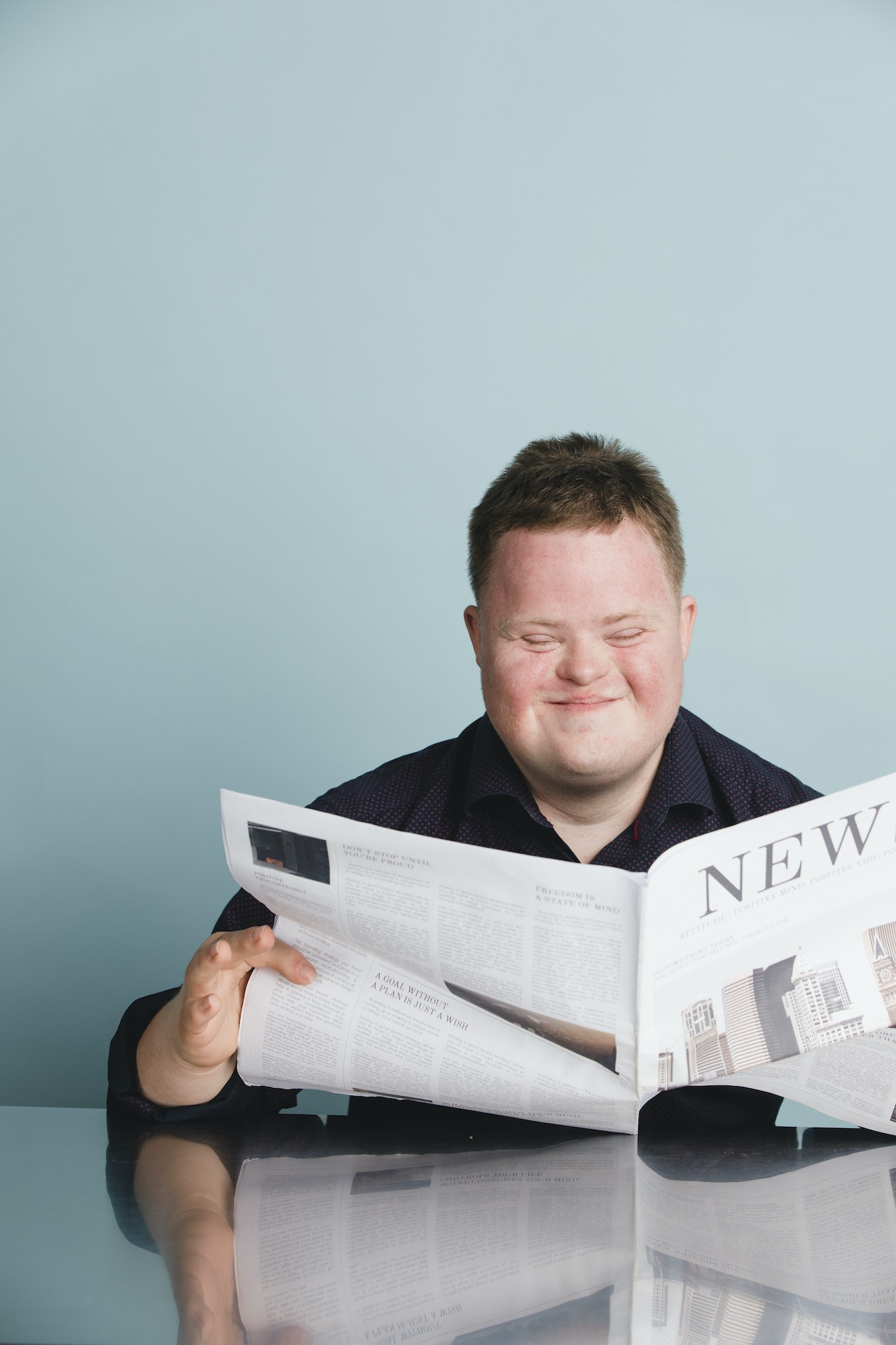 Boy with down syndrome reading a newspaper during the coronavirus pandemic
